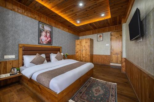a bedroom with a large bed and a flat screen tv at The Fagu Valley Retreat l Rooms and Restaurant l Family Groups & Events l Open Air Lawn l Kufri by Exotic Stays in Shimla