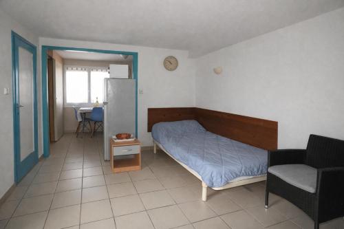 a bedroom with a bed and a chair and a table at Appartement Coloquinte-Résidence Les Glycines in Eugénie-les-Bains