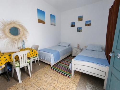 a bedroom with two beds and a table and a mirror at Dar Hkaïem in Sousse