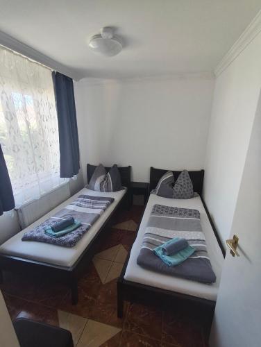 two beds sitting in a room with a window at Sunrise Apartmanház in Balatonfüred