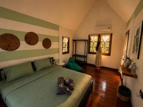 a bedroom with a bed and a woman standing in the window at Vanara Resort in Ko Chang