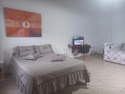 a bedroom with a bed and a television in it at chalé casa na mata céu Iluminado in Guararema