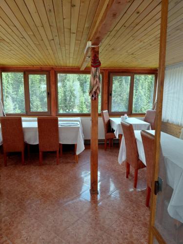 a dining room with tables and chairs and windows at Guest House Stoletnika in Yagodina