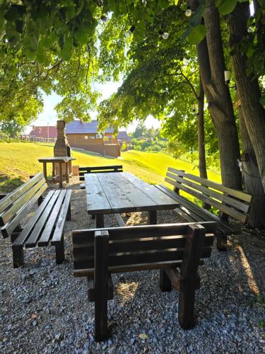 a picnic table and benches in a park with trees at LIPA houses & spa in Sopot
