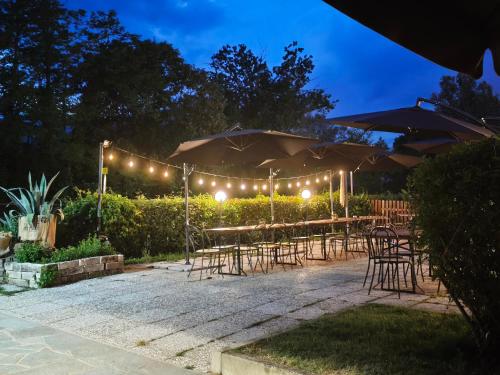 a patio with tables and chairs and umbrellas at night at Hostaria Floow in Avigliana