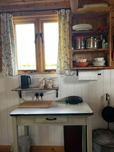 a kitchen with a table and two windows at Herdsman's Hideaway on the Wye in Fawley Station