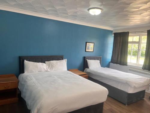 a bedroom with two beds and a blue wall at The Rivenhall Hotel in Rivenhall