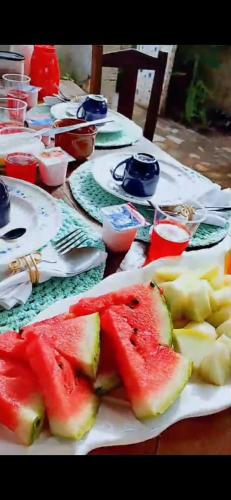 a table with plates of watermelon and fruit on them at Villa Moura Pousada in Amontada