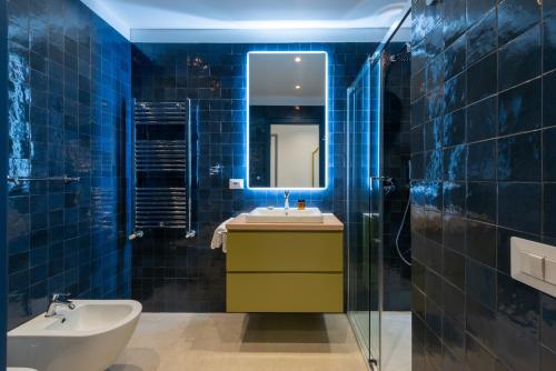 a blue tiled bathroom with a sink and a mirror at Marcello's Como Lake - Camerlata in Como