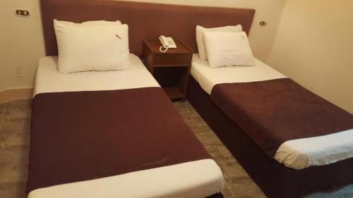 two beds in a hotel room with a phone on a table at New Sandy Hotel in Marsa Matruh