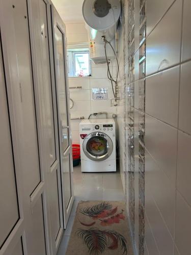 a small bathroom with a washing machine and a door at SunHouse Hostel in Karakol