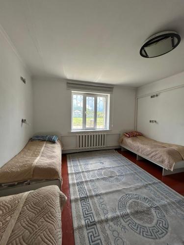 a room with two beds and a rug on the floor at SunHouse Hostel in Karakol