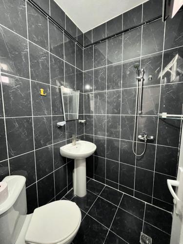 a black tiled bathroom with a toilet and a sink at Zuri Kvariati in Kvariati