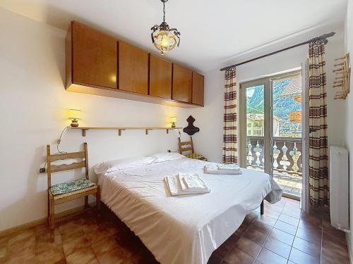 a bedroom with a bed with a chair and a window at Cesa Fraines - Apt 28 in Alba di Canazei