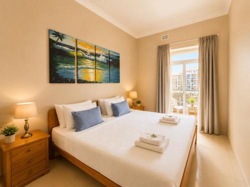 a bedroom with a large white bed and a window at Electra Guesthouse in Marsalforn
