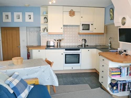a kitchen with white cabinets and a table at Ferrydown in Salcombe