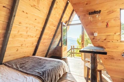 a bedroom in a log cabin with a bed and a window at Jaulares Glamping in Alaska