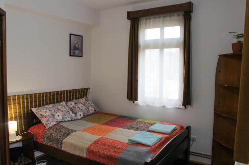 a small bedroom with a bed with a window at Casa Kővár Vendégház in Rimetea