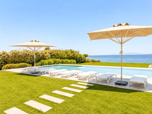 a pool with chairs and umbrellas and the ocean at Miguel Luxury Beach Front Villa in Fánai