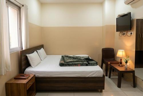 a small bedroom with a bed and a television at Hotel Aarav Grand Chandigarh in Chandīgarh