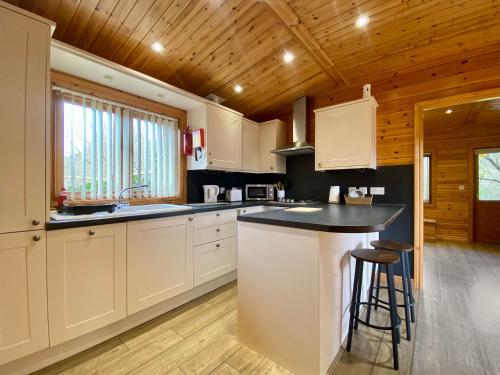 a kitchen with white cabinets and a black counter top at Pine Lodge - Uk46279 in Camerton