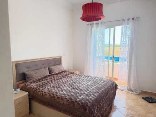 a bedroom with a bed and a large window at Apartment inside a apartment complex by the beach with public pool in Marina Smir