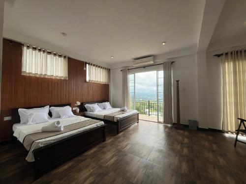 a large bedroom with two beds and a large window at Sentinels Hotel Kandy in Kandy