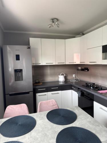a kitchen with white cabinets and a table with pink chairs at Dom nad jeziorem in Lubkowo
