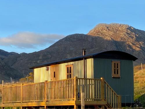 a house with a wooden deck in front of a mountain at Corran Shepherds Hut in Corran