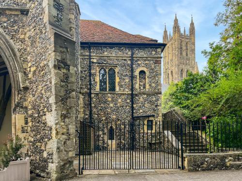 an old stone building with a gate and a cathedral at The Necessarium in Canterbury