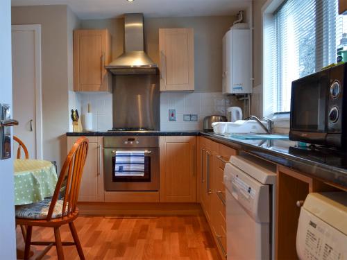 a kitchen with wooden cabinets and a stove top oven at Brae Lodge in Cullen