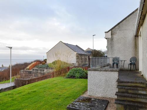 a house with a balcony with a yard at Brae Lodge in Cullen