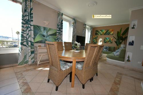 a dining room with a wooden table and wicker chairs at Duplex Luxe Vue Mer Face Palais des Festivals et Vieux Port 5 Couchages in Cannes