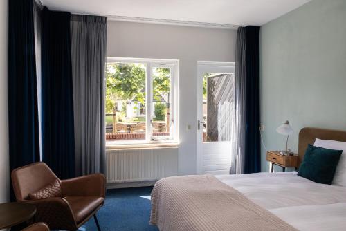 a bedroom with a bed and a chair and a window at De Watersport Heeg in Heeg