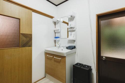 a small bathroom with a sink and a door at Irest Village Narita in Narita