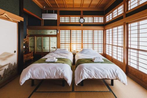 two beds in a room with windows and a clock at Irest Village Narita in Narita