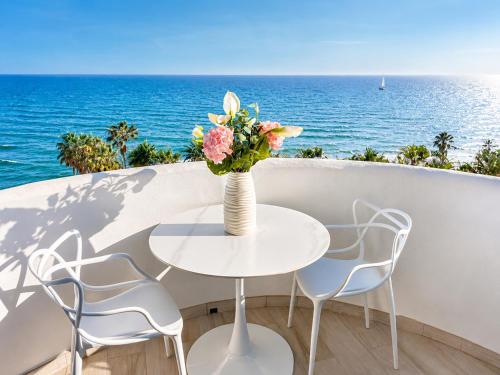a table with a vase of flowers on a balcony with the ocean at Algaida, beach apartment in Mijas Costa