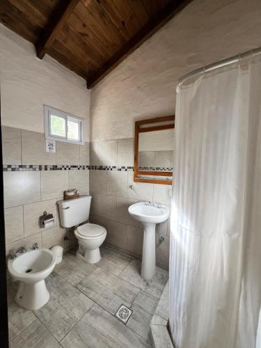a bathroom with two toilets and a sink and a shower at Cabañas El Campo in Sierra de la Ventana