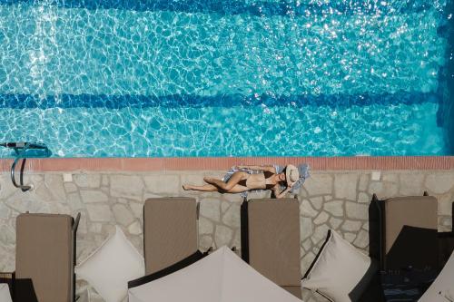 a woman laying on a wall next to a swimming pool at Hotel Sarikas in Polychrono