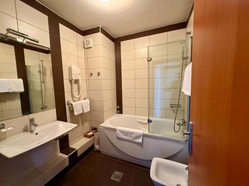 a bathroom with a tub and a sink at Hotel Kutina in Kutina