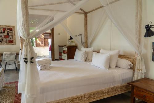a bedroom with a canopy bed with white pillows at Sun Moon Star Villas in Jarakan