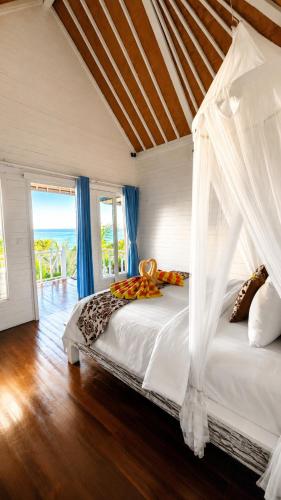 a bedroom with a bed with a canopy at Tawe Ocean Blue Villa Lembongan in Nusa Lembongan