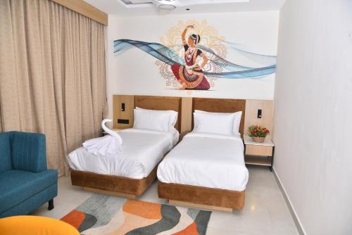 two beds in a room with a painting on the wall at Vels Grand Hotel in Kanchipuram