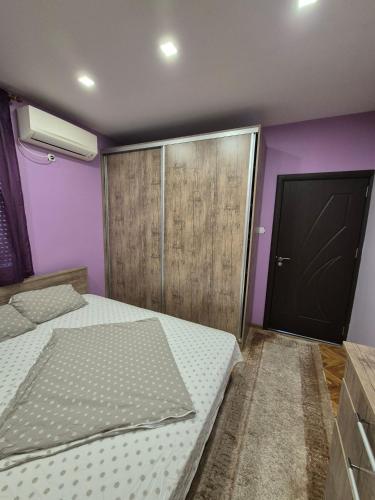 two beds in a room with purple walls and a door at Апартамент riverside in Yambol