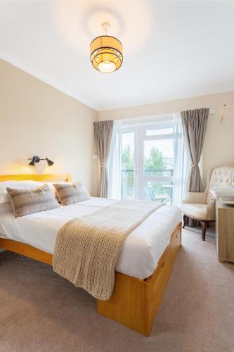a bedroom with a large bed and a chair at Avoncourt Lodge in Ilfracombe