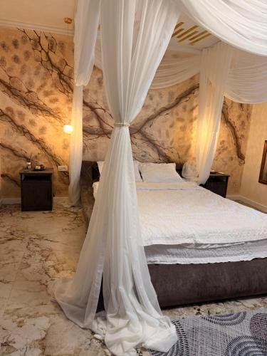 a bedroom with a canopy bed with white curtains at Guesthouse Bârlogul Balaurului in Afumaţi