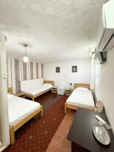 a room with two beds and a table at Pensiunea Pitaru in Calafat