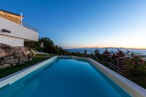 a swimming pool in front of a house with the ocean at Villa La Gioia in Terra Mala