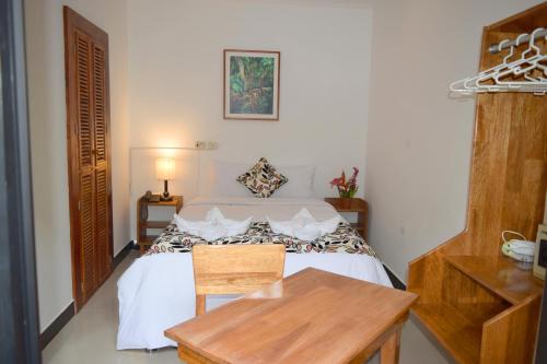 a small bedroom with a bed and a wooden table at Hotel Jungle House in Iquitos