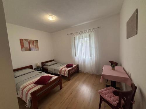 a room with two beds and a table and a window at Kuća za odmor Belvedere in Siverić